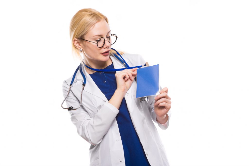 Female doctor in white coat with stethoscope and glasses shows blank badge ID card